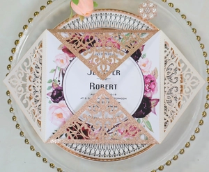 Detail of laser-cut wedding invitation with rose gold glitter sleeve and floral insert