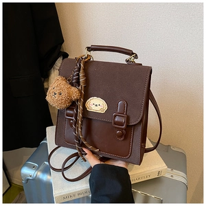 Detail of brown vintage crossbody bag with cute dog embroidery and plush bear charm