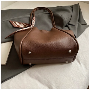 Dettaglio borsa tote marrone motivo litchi con foulard decorativo e piedini in metallo