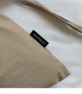 Detailopname van de kaki nylon textuur en het gestikte merklogo op de handtas
