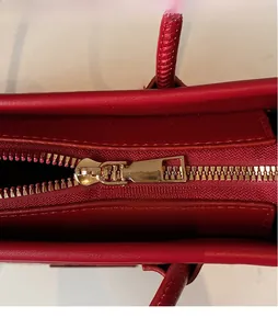 Detail shot of smooth red leather texture and high-quality gold hardware zipper