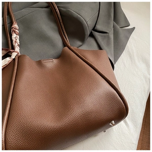 Dettaglio borsa tote in pelle marrone con foulard in seta su un blazer grigio