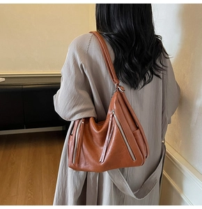 Close-up of caramel brown retro tote bag featuring silver metal zippers and long leather pulls