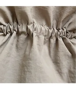 Detailopname van de lichte stoftextuur en trekkoordstiksels op de bucket bag
