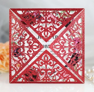 Detail of red glitter laser-cut lace wedding invitation with floral carving and white insert