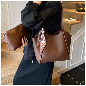 Dettaglio della borsa tote in pelle marrone con foulard in seta e pochette abbinata