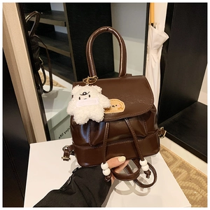 Detail view of dark brown faux leather backpack with plush bear and cartoon dog patch