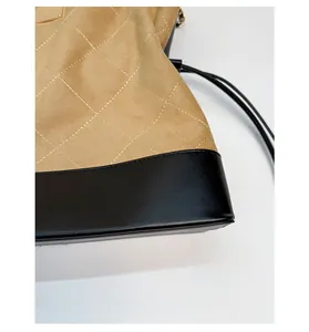 Detailed close-up of quilted suede and black leather stitching on a tote bag