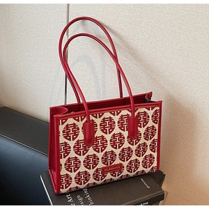 Detail of red bridal tote bag with double happiness jacquard and leather handles