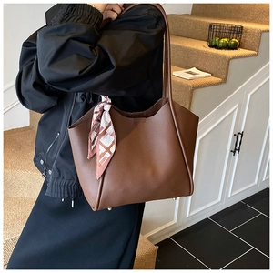 Dettaglio della borsa tote in pelle marrone scuro con sciarpa di seta floreale sul manico