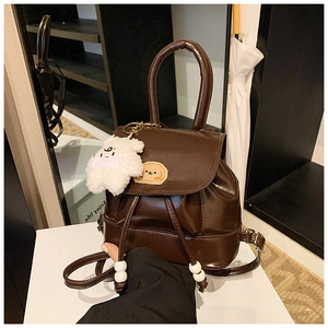 Detail view of vintage dark brown PU leather mini backpack with cute teddy bear charm