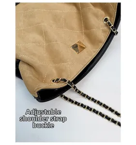 Detail of adjustable metal buckle and chain on quilted suede tote bag strap