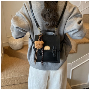Close-up of black leather backpack with cute bear pendant and cartoon dog patch on back