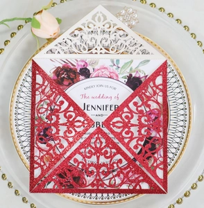 Detail of laser-cut lace wedding invitation with red glitter card and floral patterns