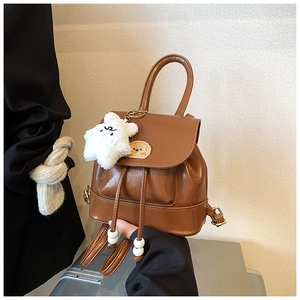Detail of a brown PU leather mini backpack with a cartoon dog patch and star pendant