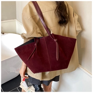 Macro view of burgundy suede tote bag featuring delicate texture and knot strap details
