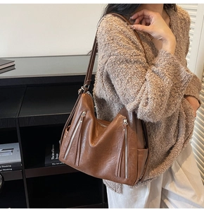 Detail of dark brown faux leather tote featuring decorative zipper tassels and retro texture