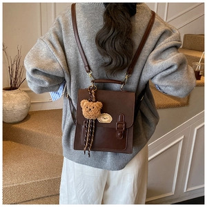 Rear view of model wearing a vintage brown leather backpack with bear charm on a staircase