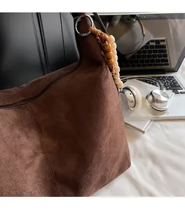 Detail of dark brown suede shoulder bag with retro wooden beads and metal ring attachment