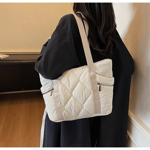 Close-up of white quilted tote bag with side metal zipper and diamond stitch detail