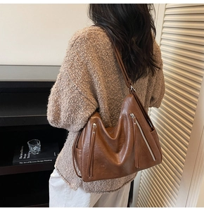 Close-up of brown vintage hobo bag with decorative vertical zippers and soft leather texture