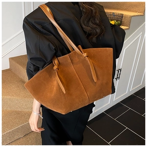 Detailed view of brown suede tote bag with knot decor shown on a model shoulder