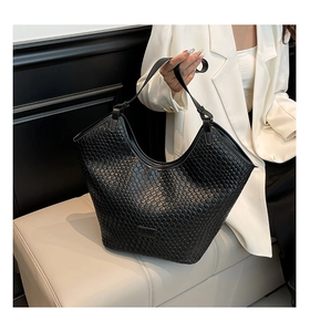 Detail view of black woven checkerboard texture on a modern faux leather tote bag
