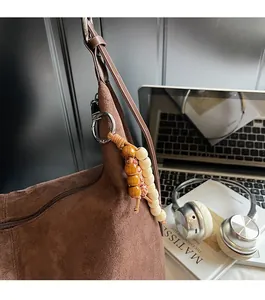 Close-up of brown suede tote bag with decorative wooden beads and off-white tassels