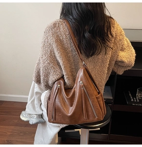 Detail of vintage brown leather hobo bag featuring side silver zippers and long tassels