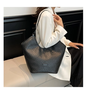 Close-up of the black woven texture and rectangular metal logo on a stylish tote bag