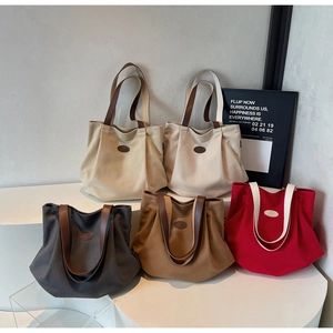 Detail of pleated canvas tote bags in five colors with PTJIA branding on a white stand