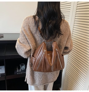 Brown leather vintage backpack for women shown being worn by a model in a cozy library