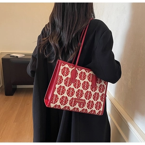 Detail of red bridal tote bag with Xi characters and leather handles on black coat
