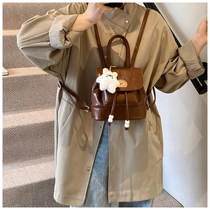 Detail of vintage brown leather backpack with drawstring closure and cute plush bear charm