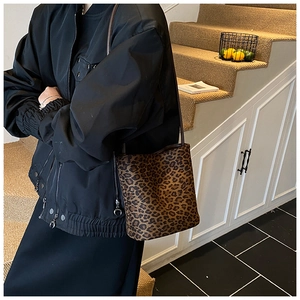 Vue détaillée du sac seau à motif léopard porté en bandoulière dans un décor élégant