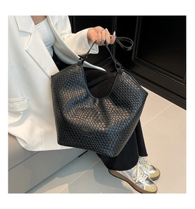 Close-up of black woven leather tote bag with checkered texture and embossed logo