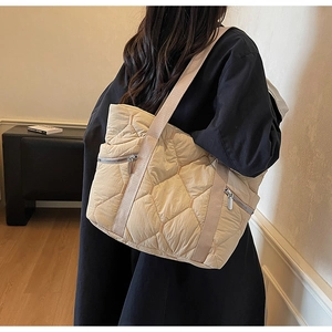 Detail of quilted beige tote bag showing high-quality nylon texture and metal zippers
