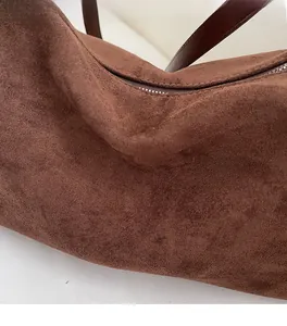 Gros plan détaillé de la texture en daim marron avec fermeture éclair et bandoulière en cuir