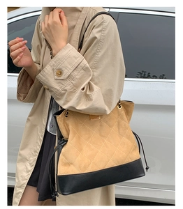 Quilted tote bag with chain strap shown on model in a stylish outdoor setting