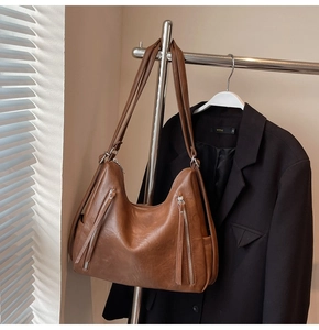 Detail of vintage brown leather tote bag showing side silver zippers and textured material