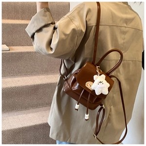 Detail view of a vintage brown mini backpack with drawstring and plush bear charm