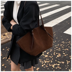 Detail of dark brown suede tote bag with knot shoulder strap in autumn street setting