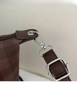 Close-up of brown checkered tote bag featuring polished silver hardware and leather strap