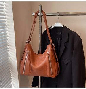 Detail of caramel brown PU leather bag with vertical silver zippers and side pockets