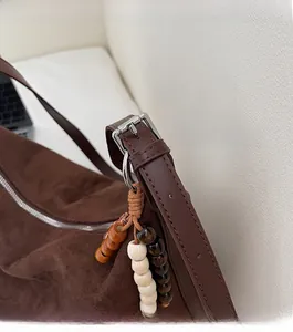 Détail du sac en daim marron foncé avec boucles argentées et breloque en perles de bois