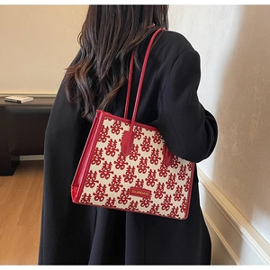 Detail of red bridal handbag featuring embroidered double happiness motifs and leather handles