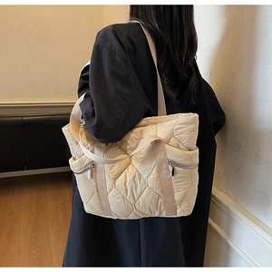 Beige quilted tote bag worn by model showing its large capacity and stylish side zippers