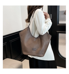 Detailed macro view of deep brown woven texture and leather brand logo on a tote bag