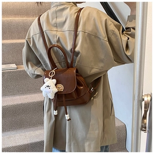Detailed view of a brown vintage backpack with drawstring closure and star plush charm