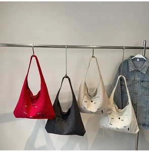 Detailansicht der TELN Canvas-Taschen in Rot, Grau und Beige am Verkaufsständer